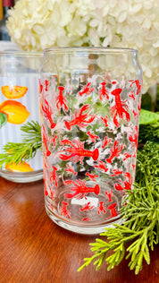 Clear glass with red lobster design on a wooden surface with greenery