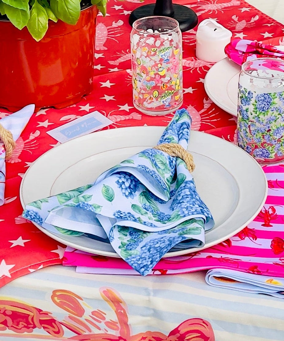 Decorated table with a red and white tablecloth, colorful napkins, and various items on a patio.