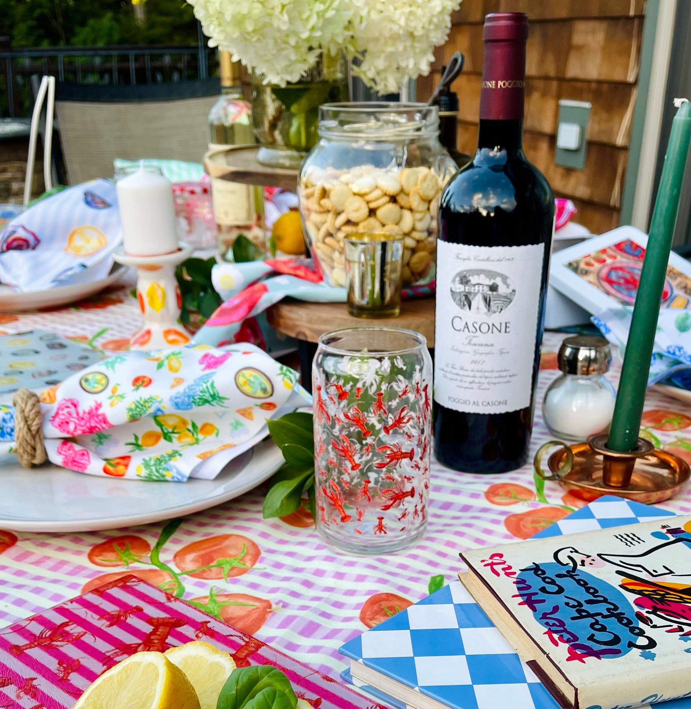 Outdoor table setting with colorful tablecloth, wine bottle, and lemon garnish.