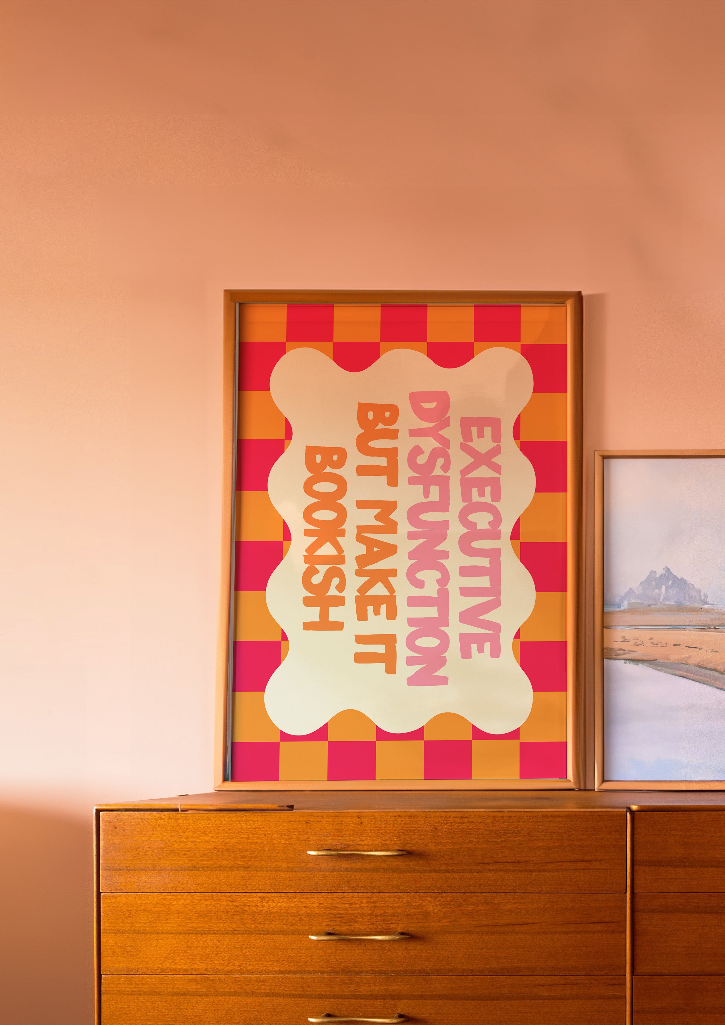 Executive Dysfunction but Make It Bookish 24x36 bookish mental health wall art poster leaning on a wooden dresser against a blush wall