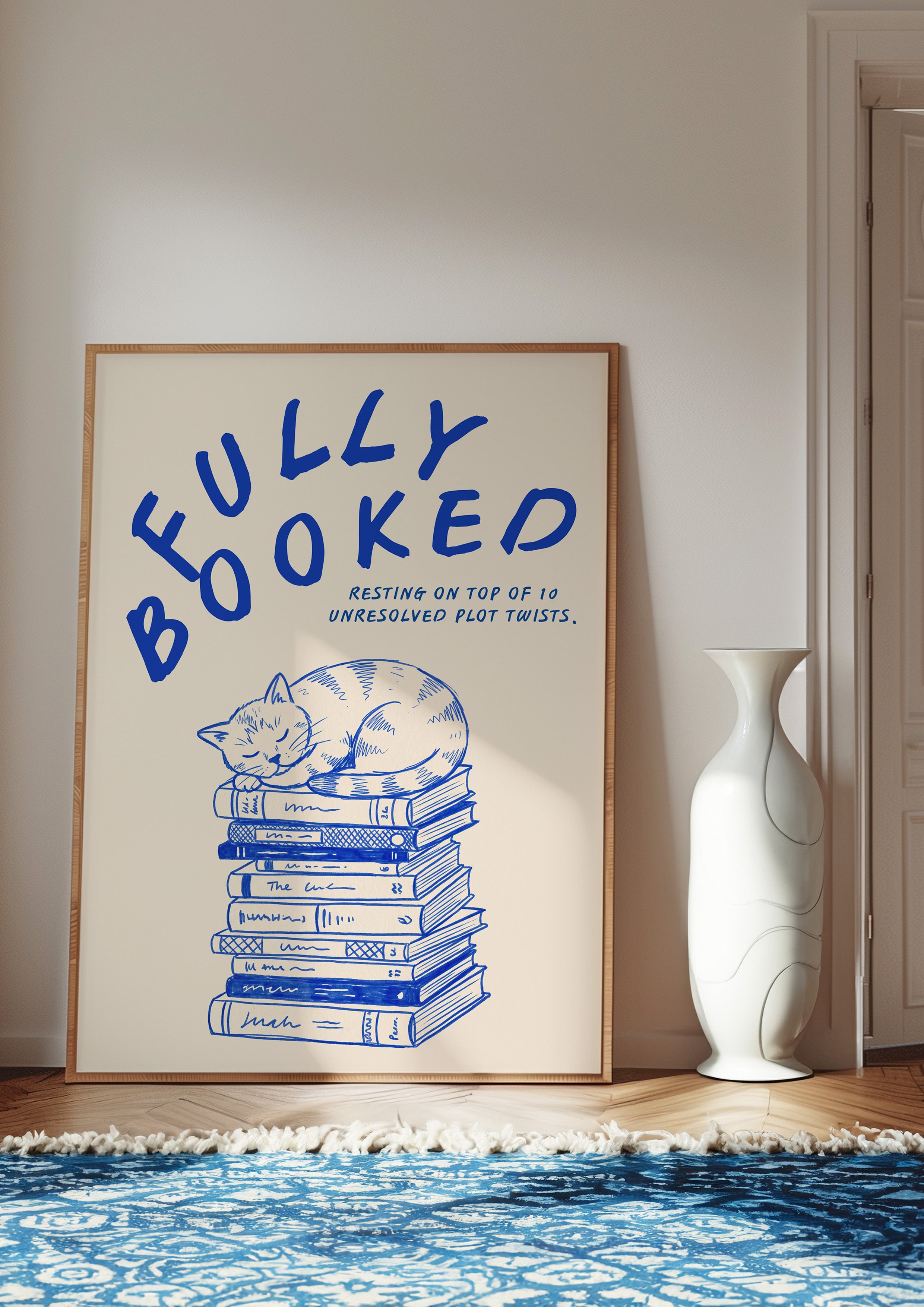 Fully Booked 24x36 bookish wall art poster leaning in a bright room on a blue patterned rug