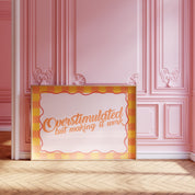 Overstimulated but Making It Work horizontal 24x36 mental health wall art poster leaning against a pink paneled wall on a herringbone wood floor