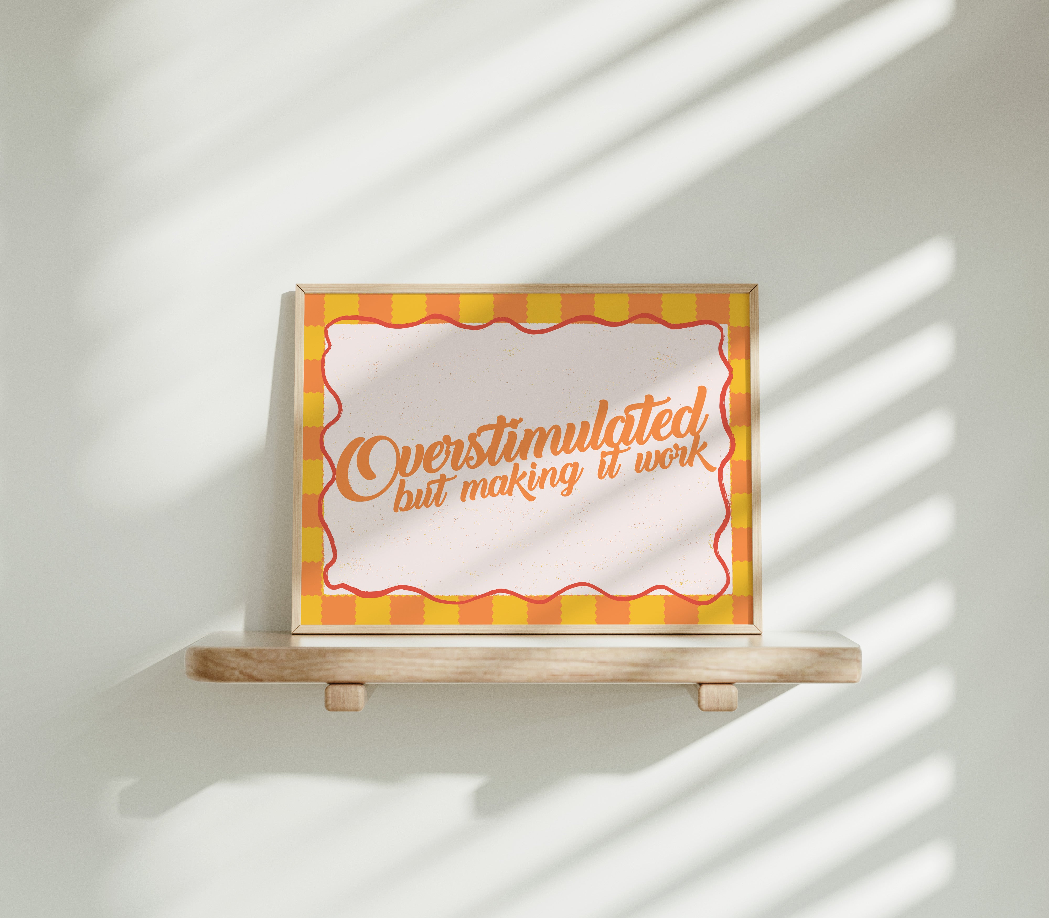 Overstimulated but Making It Work horizontal 24x36 mental health wall art poster displayed on a wooden shelf against a sunlit white wall