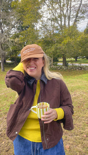 Woman wearing the brown Books & Wine embroidered corduroy hat with a mug outdoors