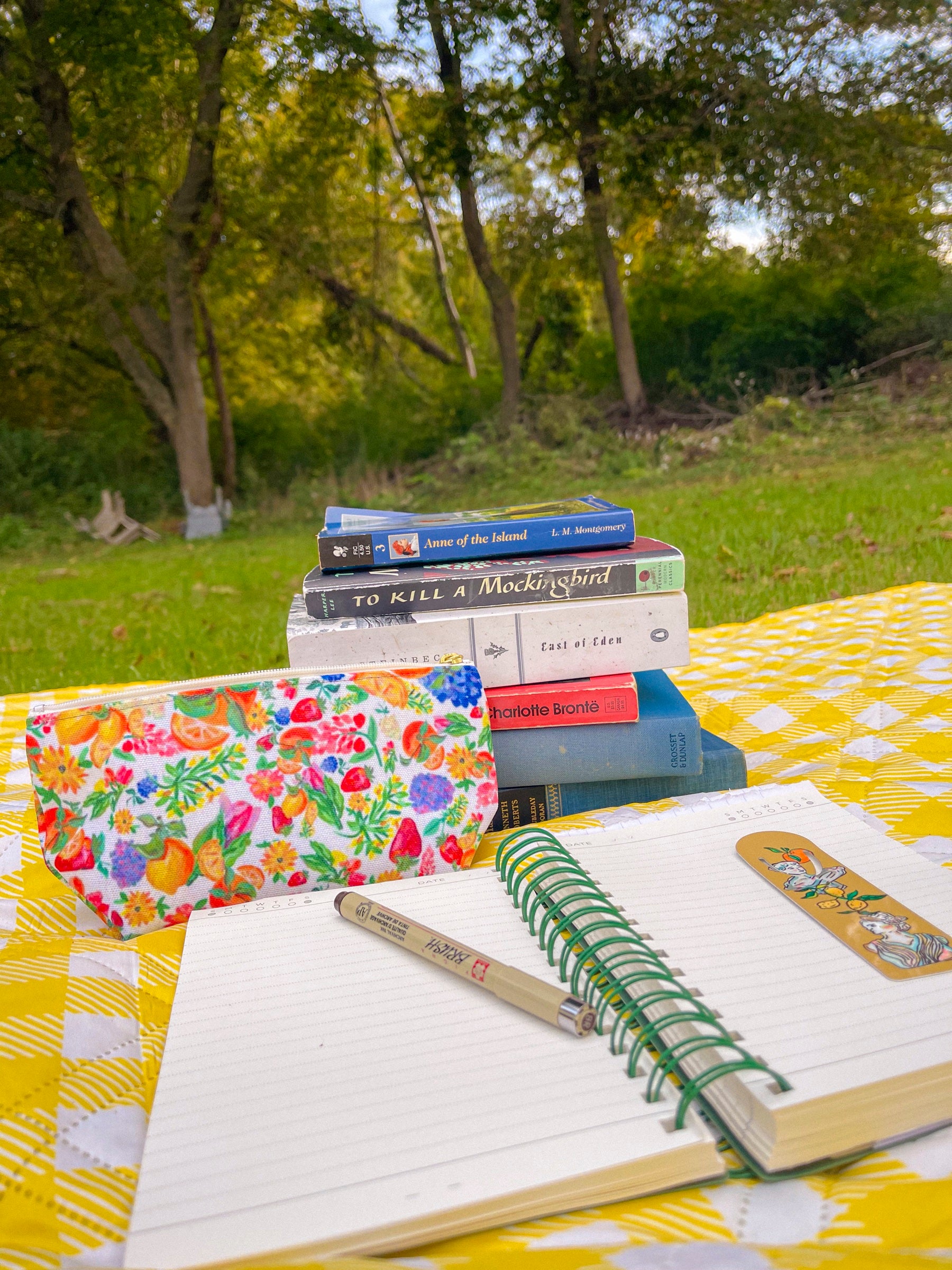 Citrus Blossom accessory pouch with a stack of books and an open notebook outdoors
