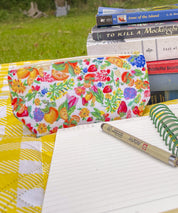 Citrus Blossom accessory pouch with a stack of books and an open notebook outdoors