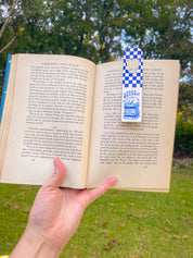 Fully Booked blue checkerboard metal bookmark in an open book outdoors