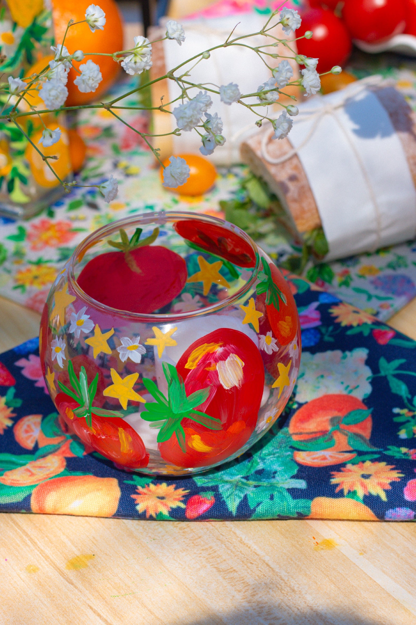 Hand-painted tomato glass bowl on a colorful floral napkin