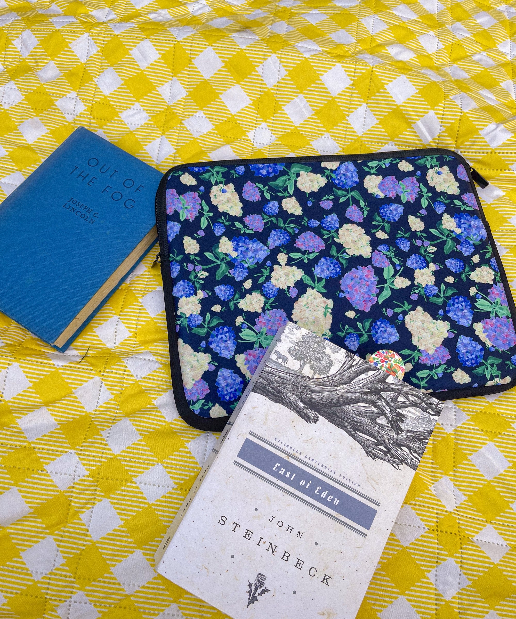 Painted Hydrangeas in Navy sleeve with East of Eden on a yellow gingham blanket