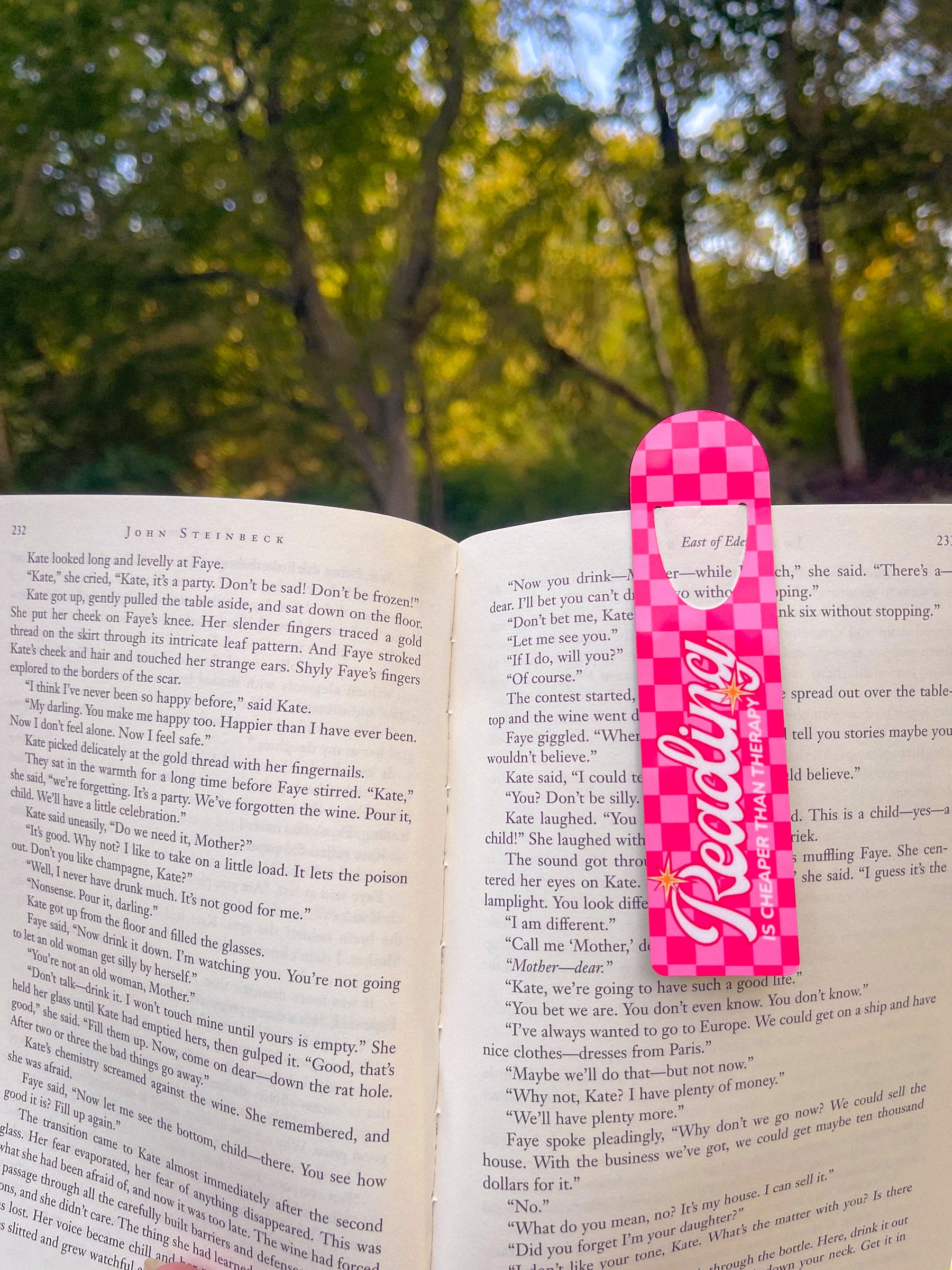 Pink Reading metal bookmark marking a page outdoors
