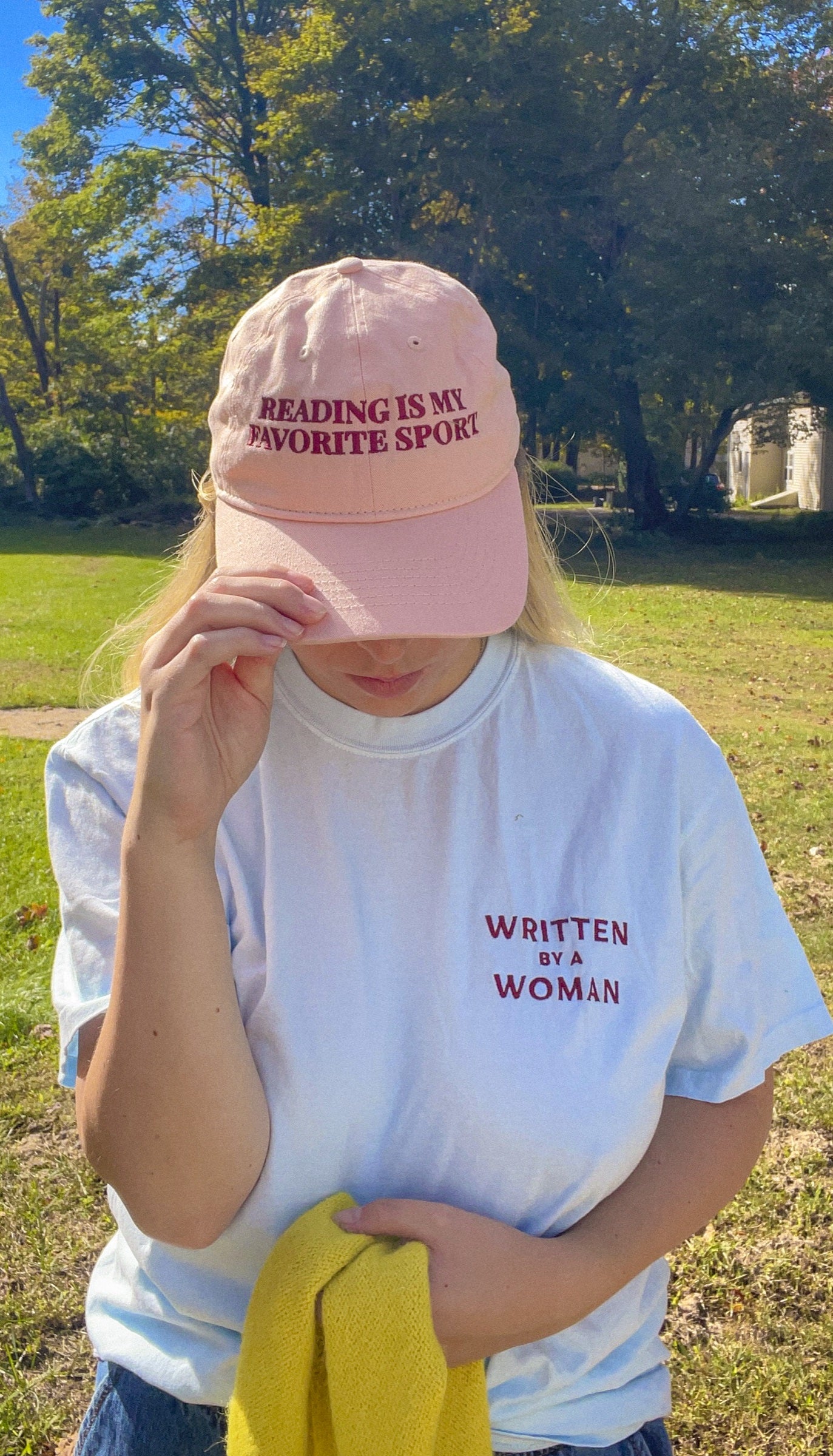 Pink Reading Is My Favorite Sport cap worn with a white tee outdoors