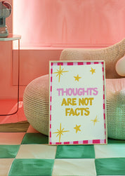 Thoughts Are Not Facts 24x36 mental health wall art poster propped beside a woven pouf on a green checkered floor