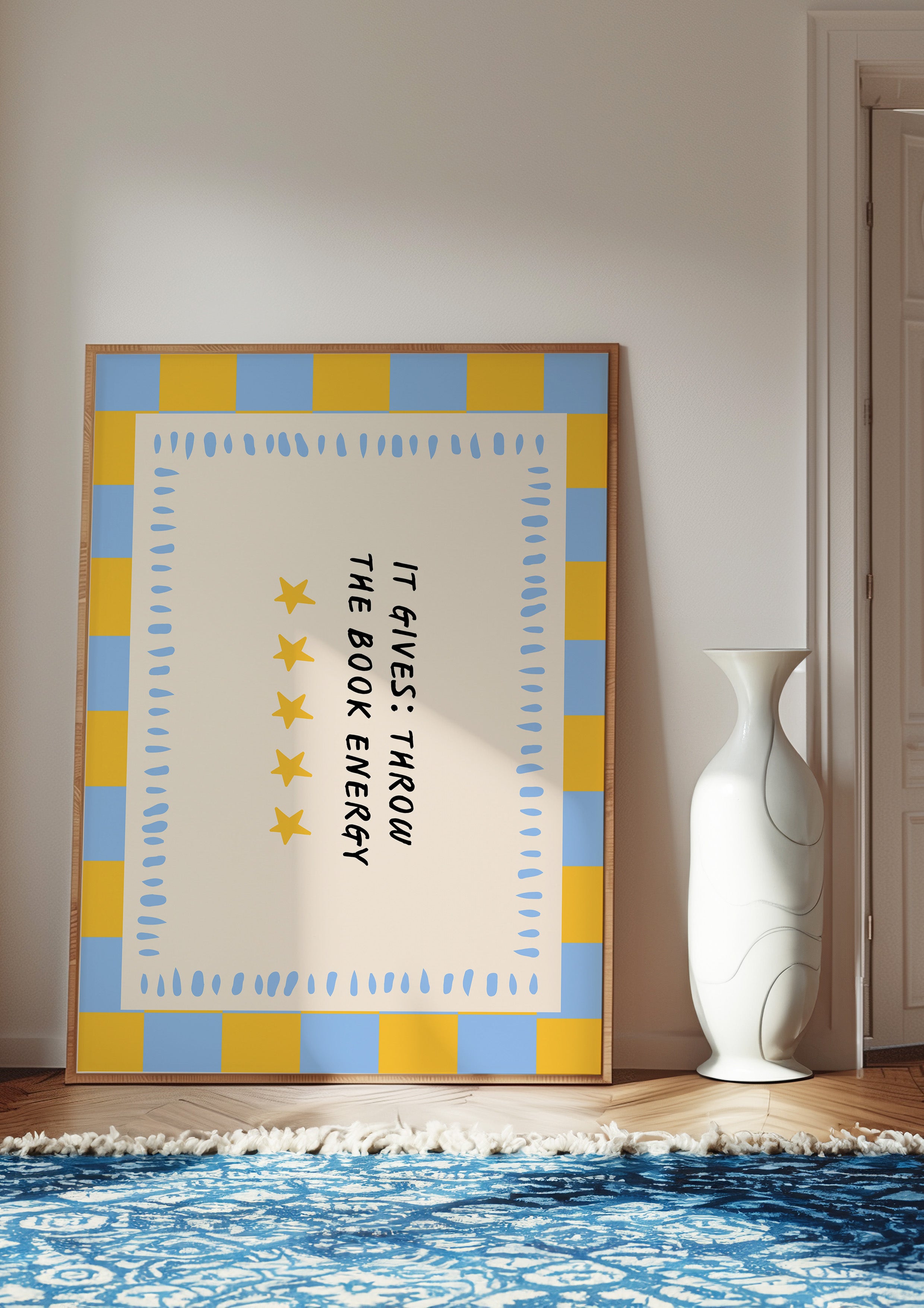 It Gives: Throw the Book Energy 24x36 bookish wall art poster leaning in a bright room on a blue patterned rug