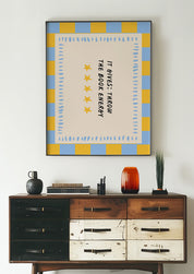 It Gives: Throw the Book Energy 24x36 bookish wall art poster framed above a vintage wood dresser