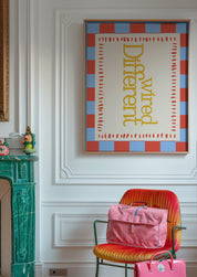 Wired Different 24x36 mental health wall art poster framed on a white paneled wall beside a green marble fireplace